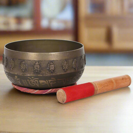 Tibetan singing bowl with wooden and red velvet beater on a white background
